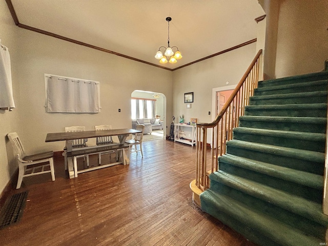 foyer entrance with dark hardwood / wood-style floors, crown molding, a high ceiling, and a chandelier