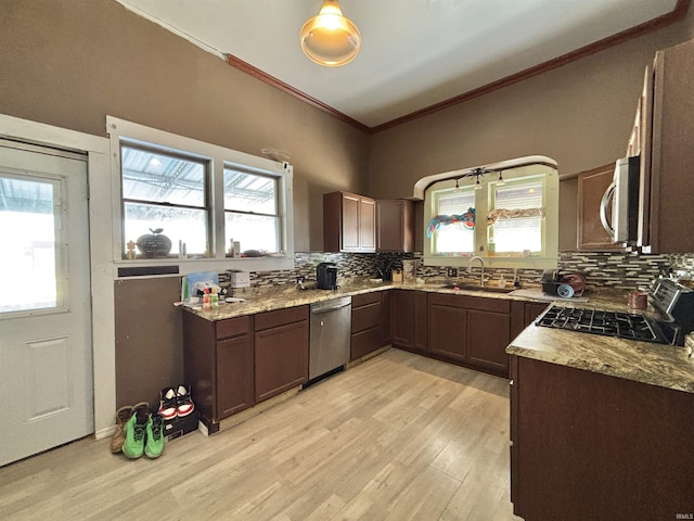 kitchen featuring tasteful backsplash, ornamental molding, light hardwood / wood-style floors, and appliances with stainless steel finishes