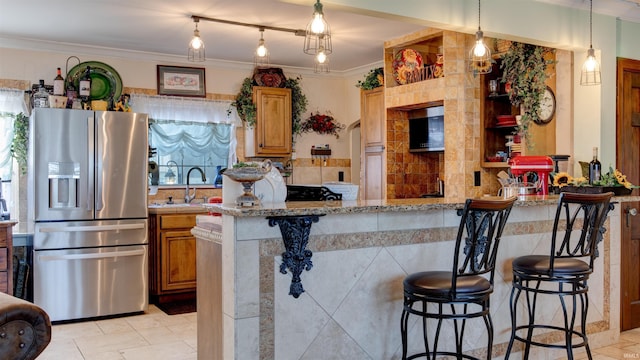 kitchen with a kitchen breakfast bar, light stone countertops, stainless steel fridge with ice dispenser, and kitchen peninsula