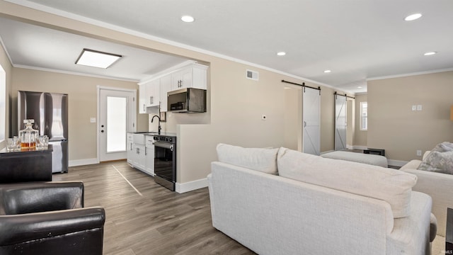 living room with hardwood / wood-style floors, crown molding, sink, wine cooler, and a barn door