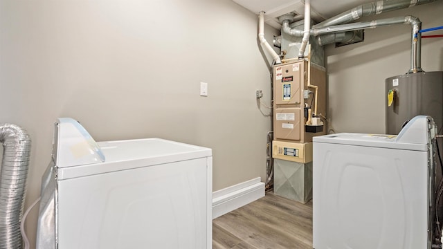 clothes washing area featuring washing machine and clothes dryer, light hardwood / wood-style flooring, and gas water heater