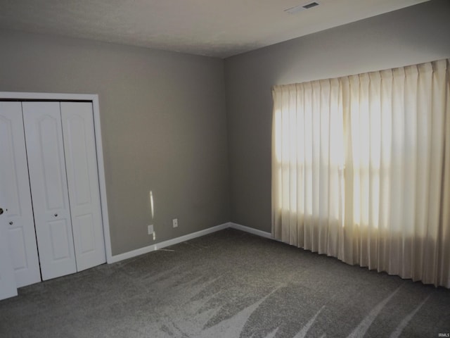 unfurnished bedroom featuring a closet and dark carpet