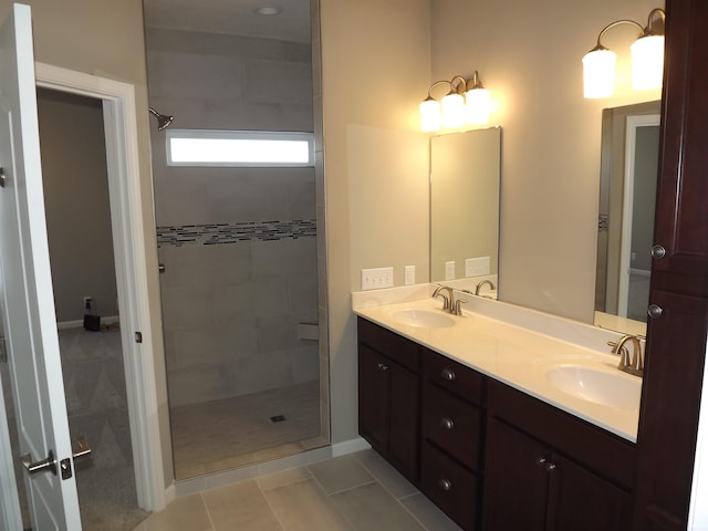 bathroom with tile patterned flooring, a tile shower, and vanity