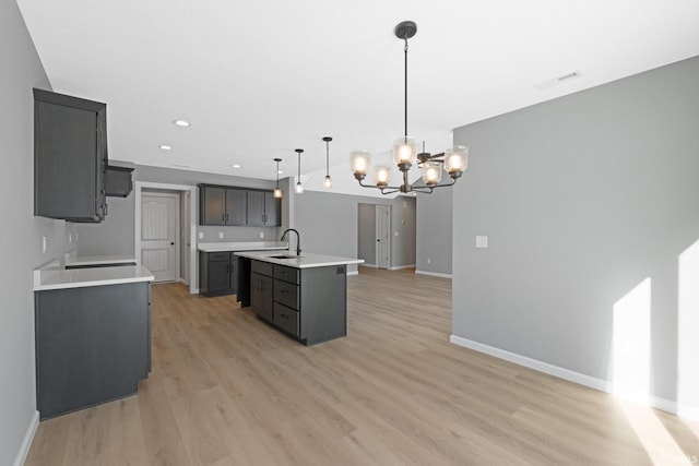 kitchen with a notable chandelier, a center island with sink, sink, decorative light fixtures, and light hardwood / wood-style floors
