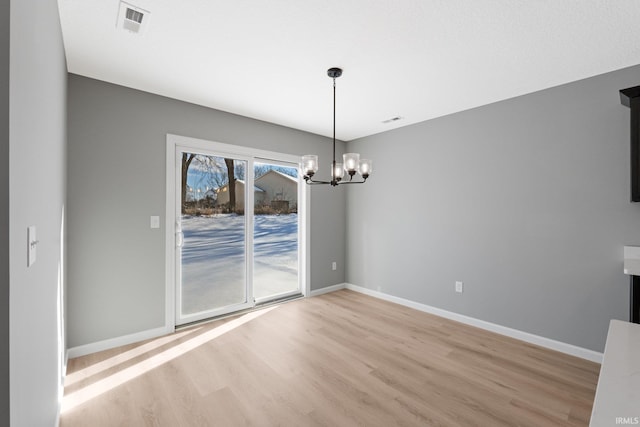 unfurnished dining area featuring a chandelier and light hardwood / wood-style floors