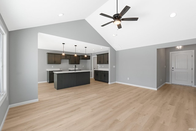 kitchen with ceiling fan, sink, pendant lighting, a center island with sink, and light wood-type flooring