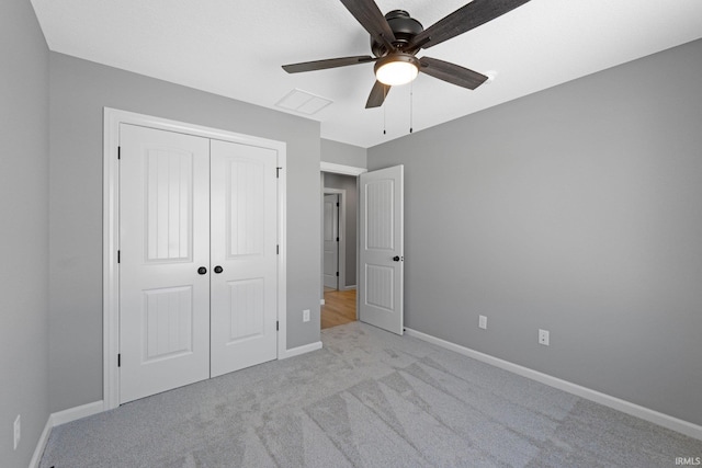 unfurnished bedroom featuring ceiling fan, a closet, and light carpet