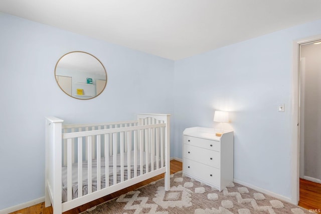 bedroom with a crib and light hardwood / wood-style flooring