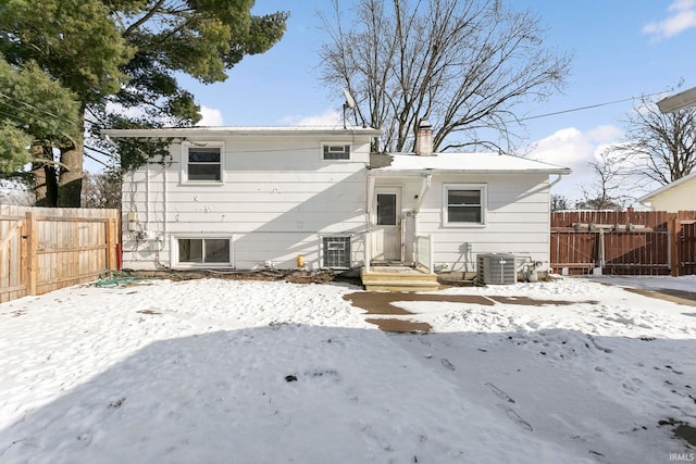 snow covered back of property with central AC