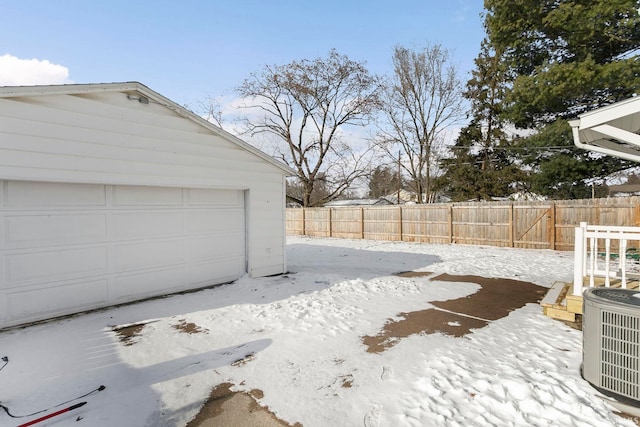 snowy yard featuring an outdoor structure, central AC unit, and a garage