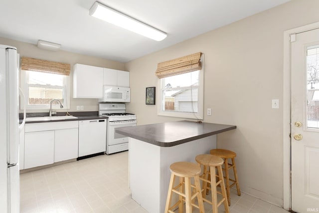 kitchen featuring kitchen peninsula, a kitchen breakfast bar, white appliances, sink, and white cabinets