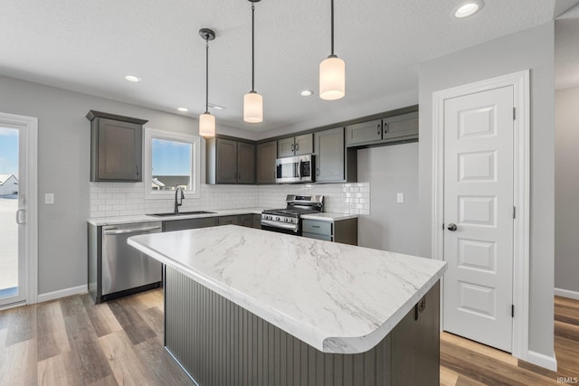 kitchen featuring decorative backsplash, stainless steel appliances, sink, a center island, and hanging light fixtures