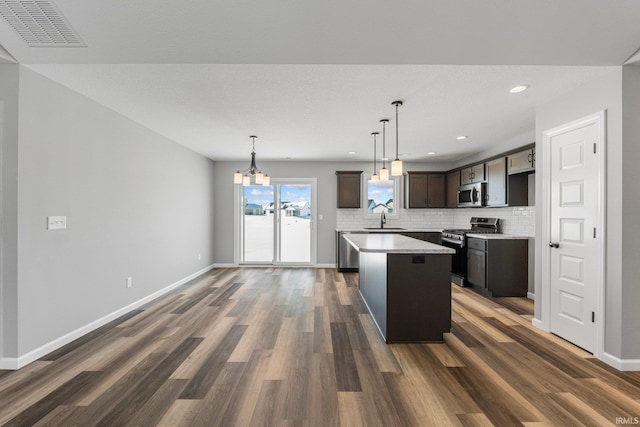 kitchen featuring pendant lighting, a center island, sink, appliances with stainless steel finishes, and dark brown cabinets