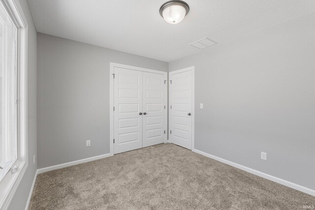 unfurnished bedroom with a closet and light colored carpet