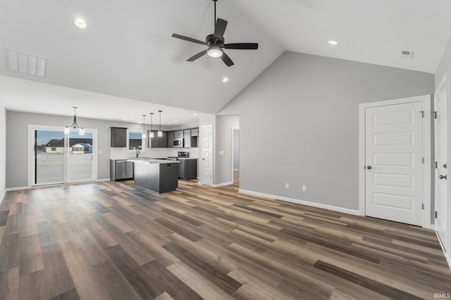 unfurnished living room with ceiling fan with notable chandelier, dark hardwood / wood-style floors, high vaulted ceiling, and sink