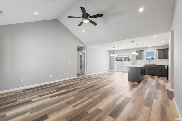 living room with sink, high vaulted ceiling, wood-type flooring, and ceiling fan with notable chandelier