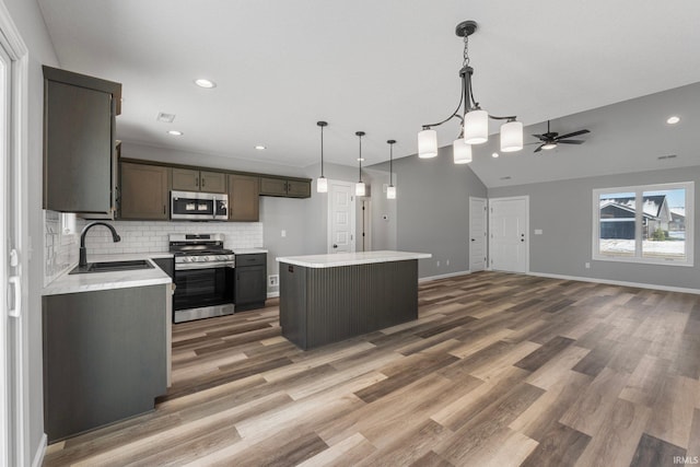 kitchen with appliances with stainless steel finishes, backsplash, a center island, dark hardwood / wood-style floors, and lofted ceiling