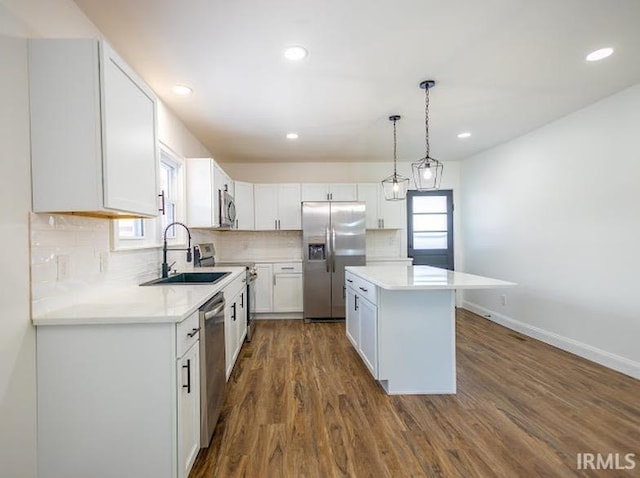 kitchen with white cabinets, decorative light fixtures, decorative backsplash, and appliances with stainless steel finishes