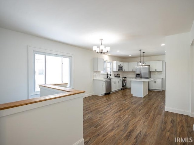 kitchen featuring sink, a center island, decorative light fixtures, white cabinets, and appliances with stainless steel finishes