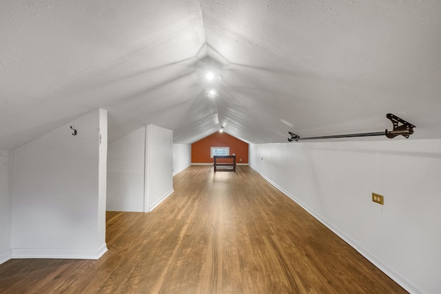 additional living space with hardwood / wood-style flooring and lofted ceiling