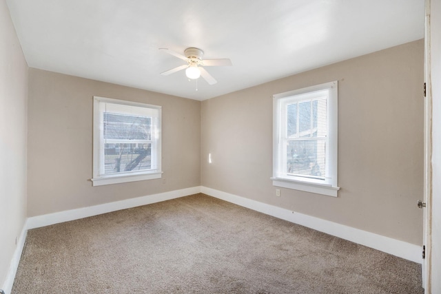 carpeted spare room featuring ceiling fan and plenty of natural light