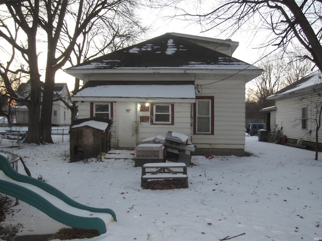 snow covered back of property with a playground