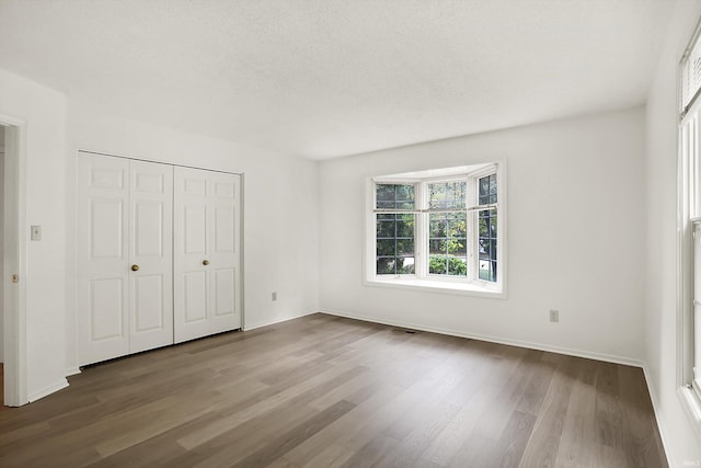 unfurnished bedroom featuring hardwood / wood-style floors, a textured ceiling, and a closet