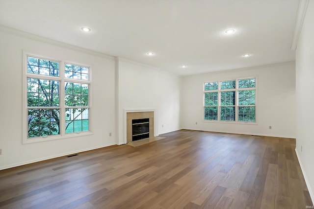 unfurnished living room featuring dark hardwood / wood-style floors, ornamental molding, and a tiled fireplace