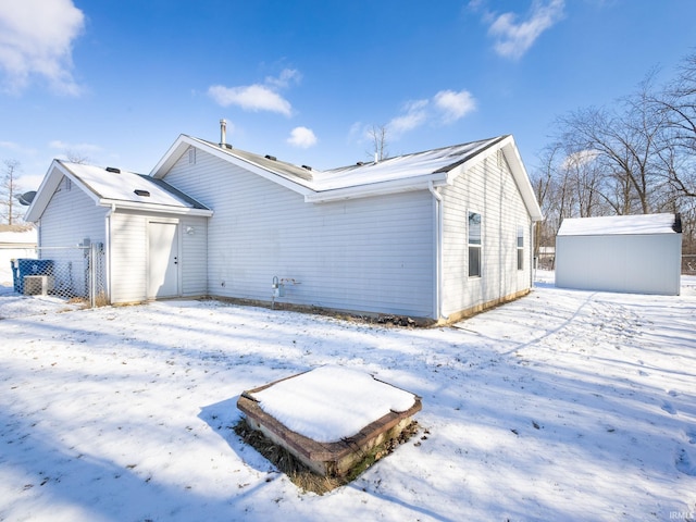 snow covered rear of property featuring a shed