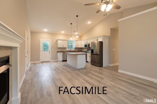 kitchen featuring a center island, white cabinets, a fireplace, decorative light fixtures, and stainless steel appliances