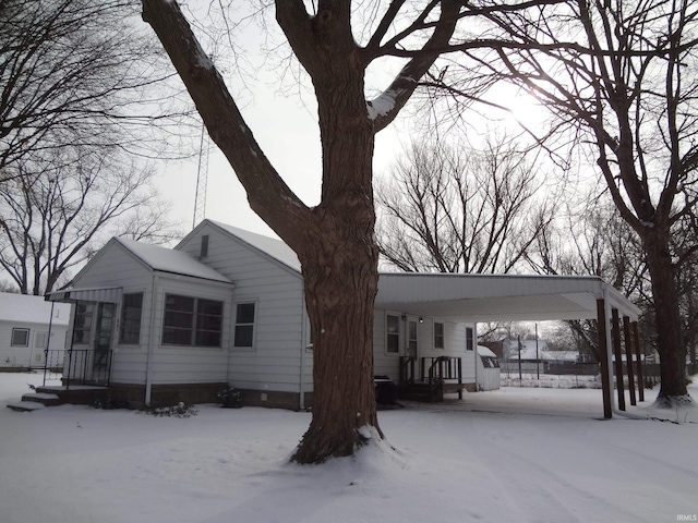 snow covered back of property with a carport