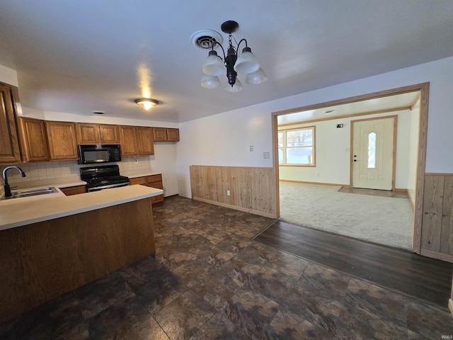 kitchen featuring black appliances, sink, decorative light fixtures, a notable chandelier, and kitchen peninsula