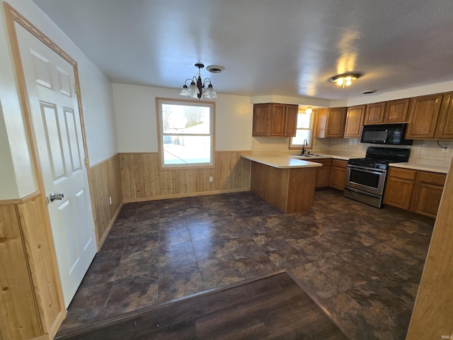 kitchen with kitchen peninsula, stainless steel range with gas cooktop, plenty of natural light, and hanging light fixtures