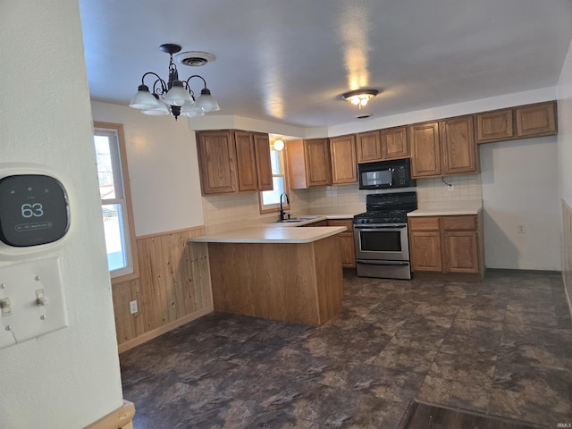 kitchen featuring sink, hanging light fixtures, stainless steel gas range oven, kitchen peninsula, and a chandelier