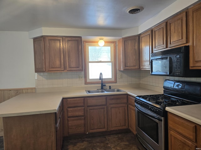 kitchen with kitchen peninsula, decorative backsplash, sink, and stainless steel range with gas stovetop