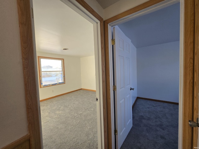 hall featuring dark colored carpet and lofted ceiling