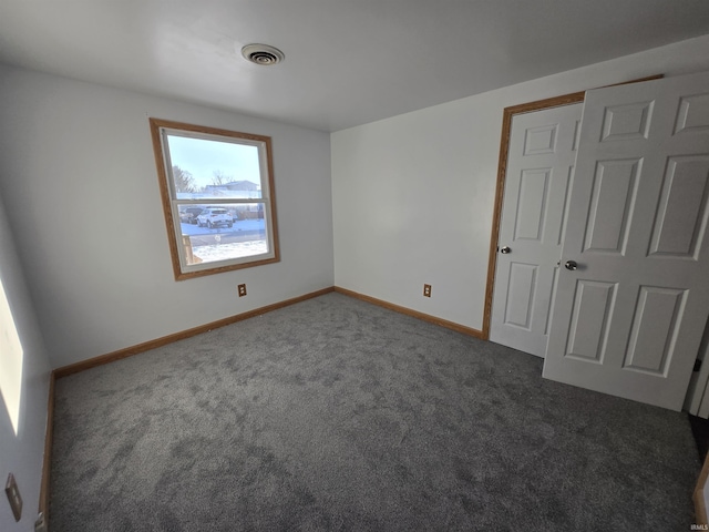 unfurnished bedroom featuring a closet and dark colored carpet