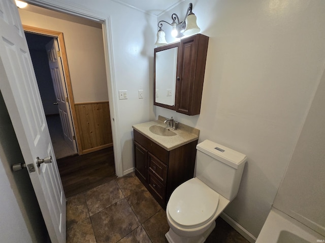 bathroom featuring vanity, toilet, and wooden walls