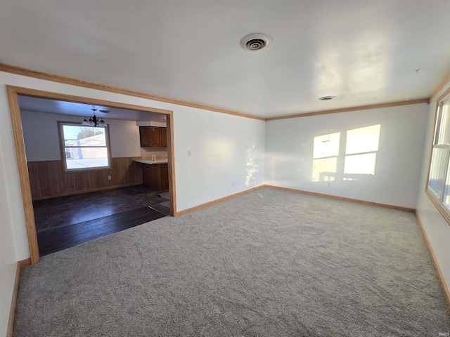 empty room featuring dark colored carpet, a chandelier, and ornamental molding