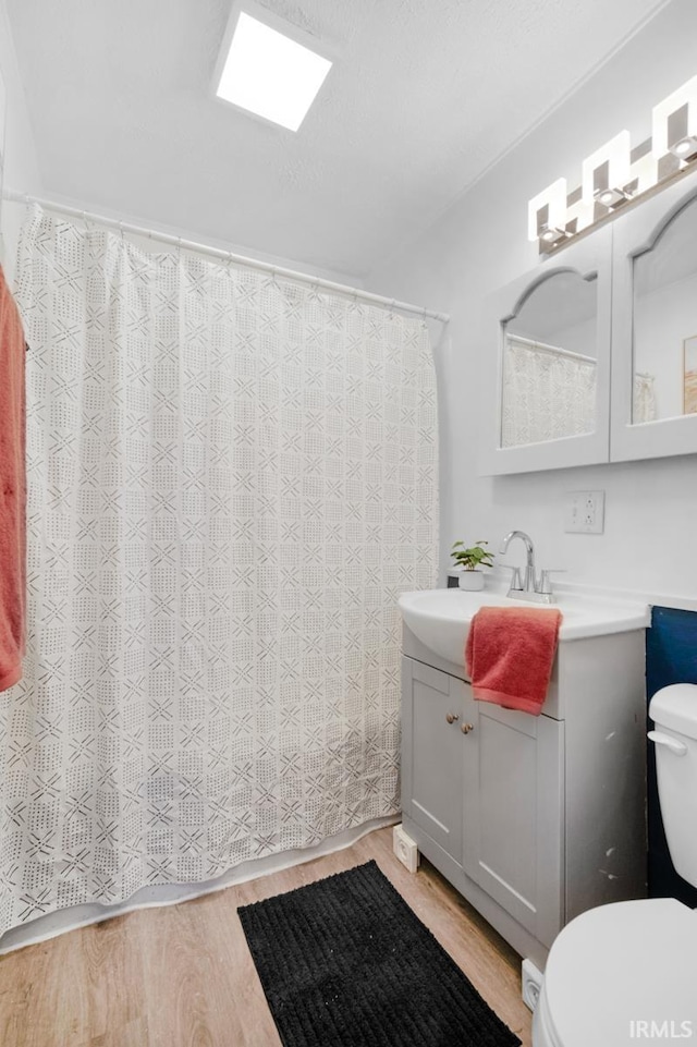 bathroom with wood-type flooring, vanity, and toilet