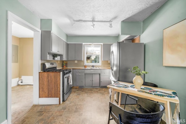 kitchen with sink, rail lighting, stainless steel appliances, a textured ceiling, and gray cabinets