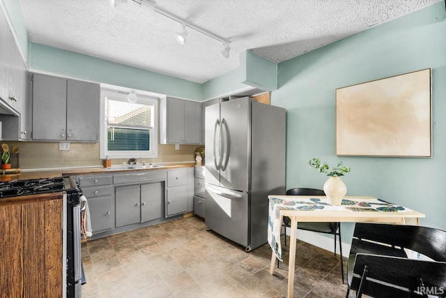 kitchen featuring rail lighting, gray cabinets, sink, and stainless steel appliances