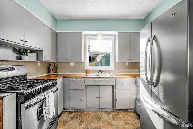 kitchen featuring range with gas stovetop, gray cabinets, sink, and stainless steel refrigerator