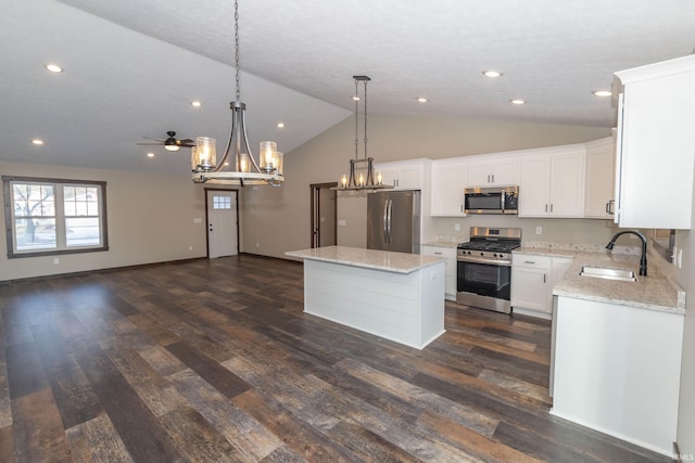 kitchen with sink, white cabinetry, stainless steel appliances, a kitchen island, and decorative light fixtures