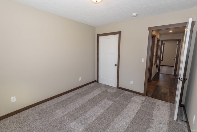 unfurnished bedroom with dark colored carpet and a textured ceiling