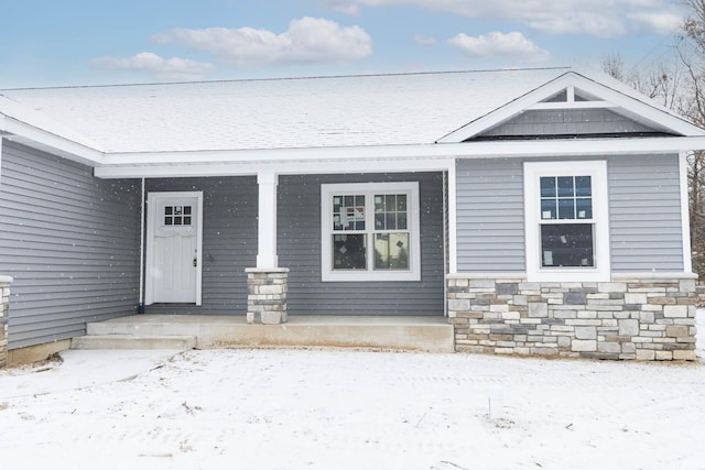 snow covered property entrance featuring a porch