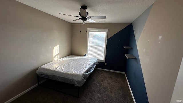 bedroom featuring dark colored carpet, a textured ceiling, and ceiling fan