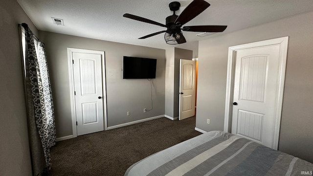 unfurnished bedroom featuring two closets, dark carpet, and ceiling fan