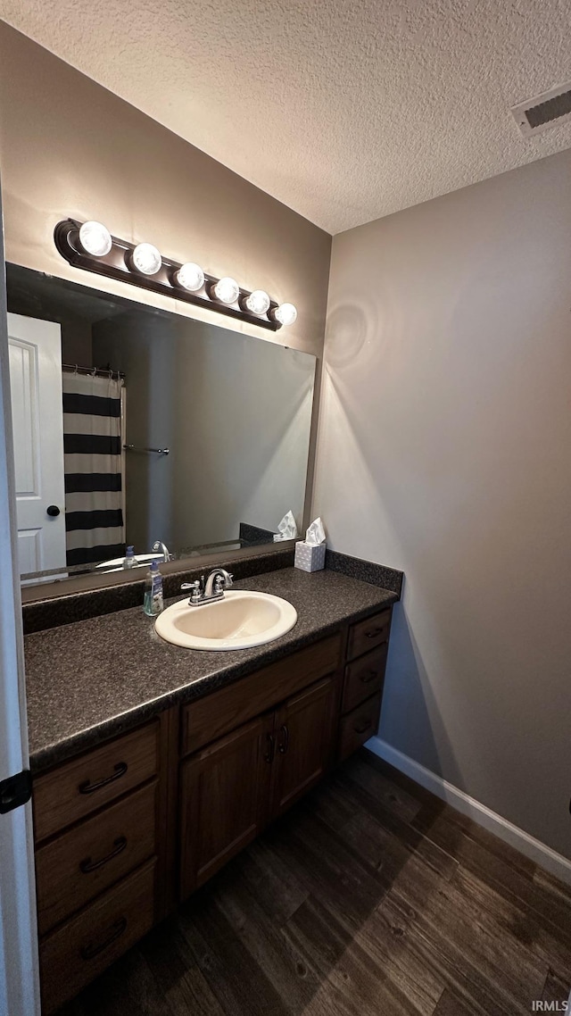 bathroom with hardwood / wood-style floors, vanity, and a textured ceiling