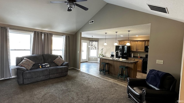 living room featuring dark colored carpet, sink, vaulted ceiling, ceiling fan, and a textured ceiling